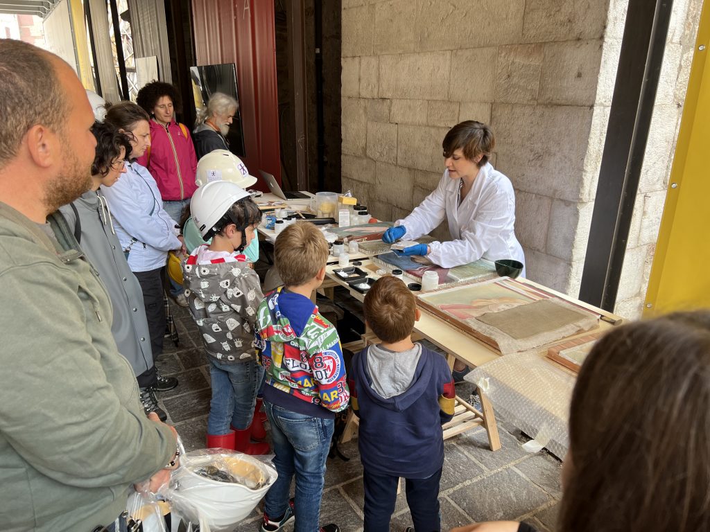 Aspasia Formichetti mostra ai bambini materiali e strumenti per il restauro degli affreschi.
